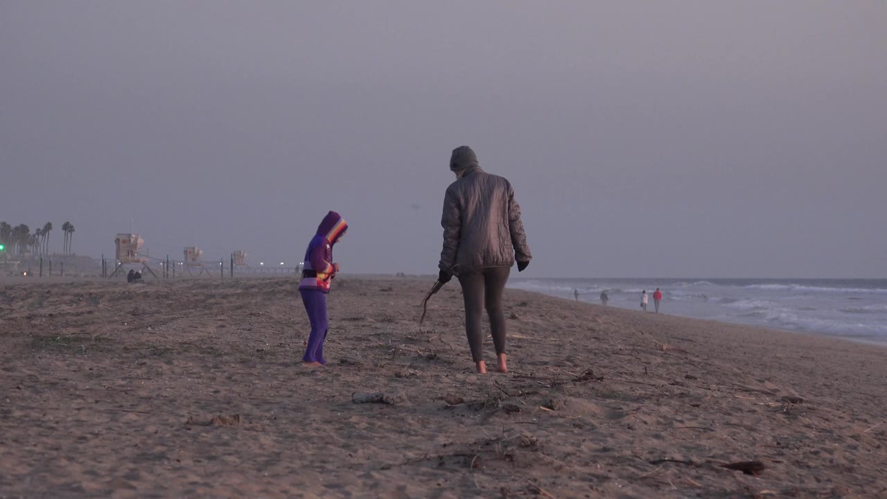 Adult and child walking along the beach at dusk