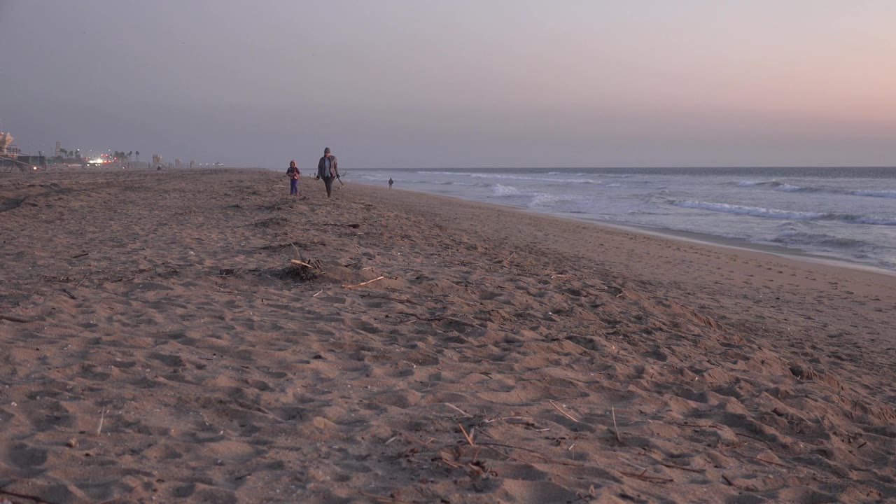 Beachgoers strolling along a dim shoreline