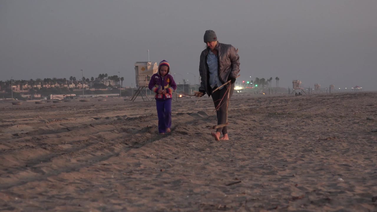 Girl and woman walking closer on beach sand.