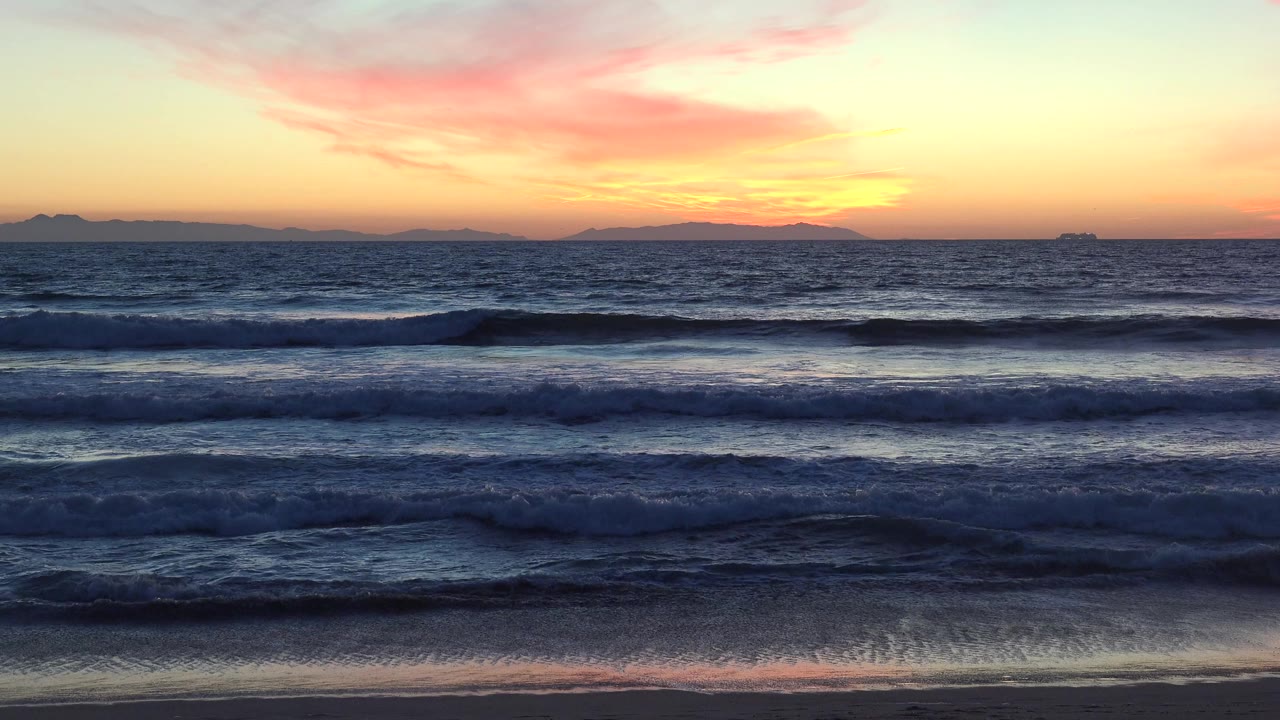 Huntington Beach, California sunset over layered ocean waves, with pink clouds above the horizon and no visible people.