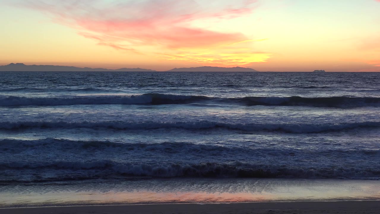 Huntington Beach, California beach view with wet sand at the bottom edge, multiple wave bands moving shoreward, and no visible people.