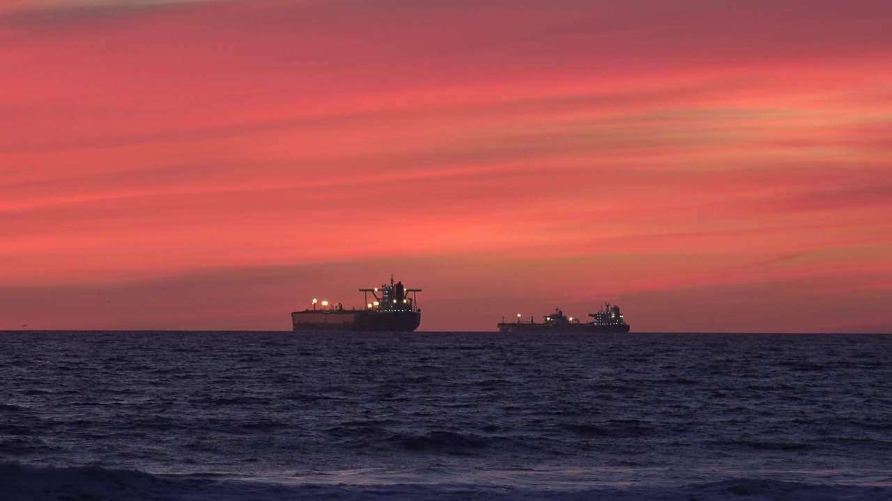 Two ships offshore with sunset clouds above