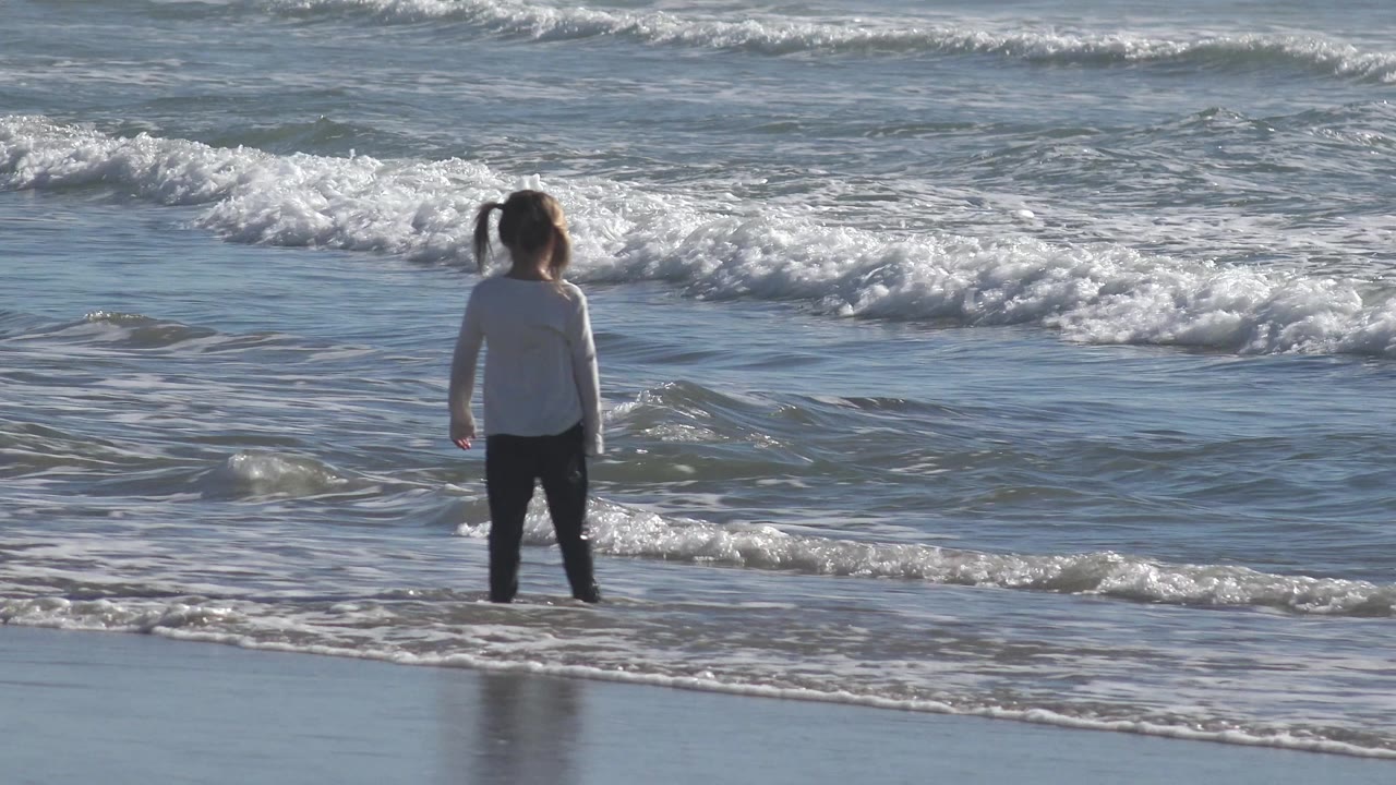 Child at the waterline with waves breaking ahead.