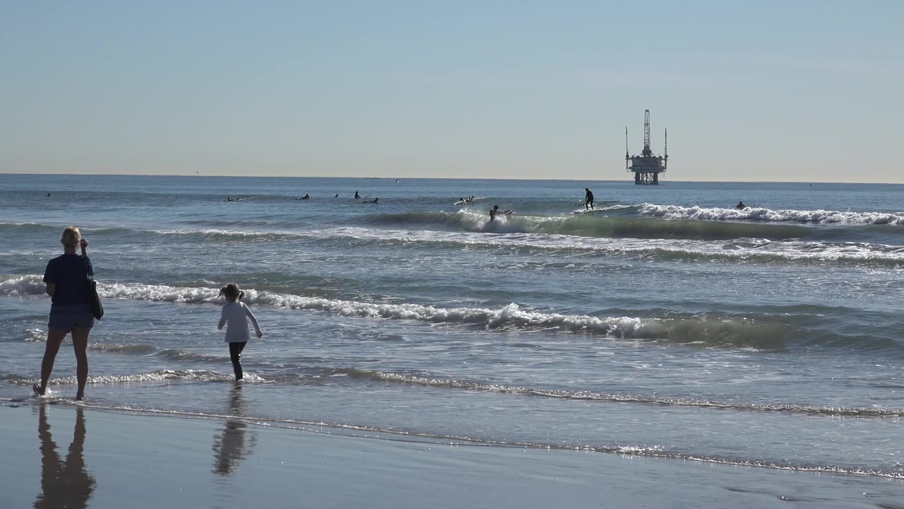 Parent and child walking farther apart near incoming waves.