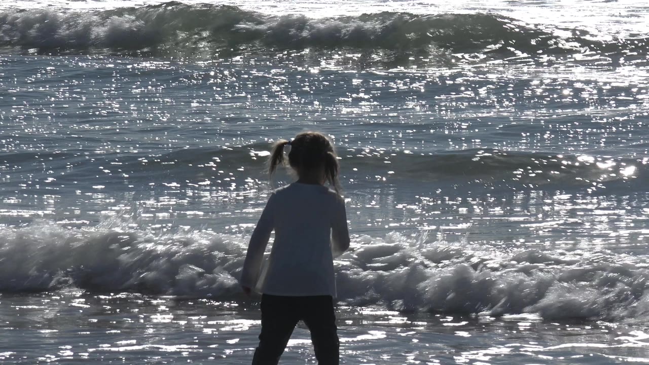 Child near foamy water at the shoreline.