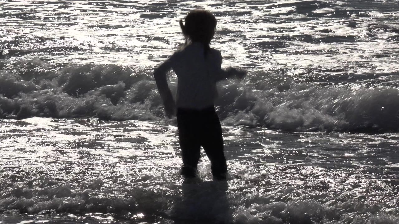 Girl turning in foamy surf beside a breaking wave.