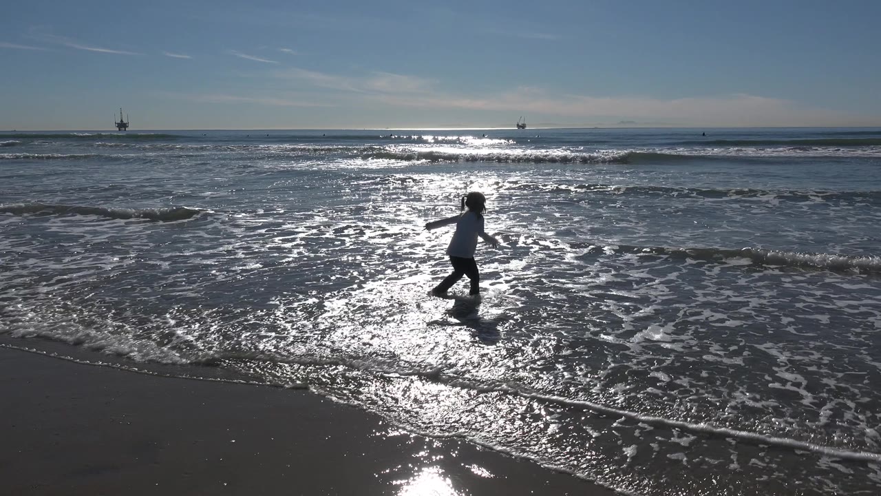 Child stepping through reflective shallow surf