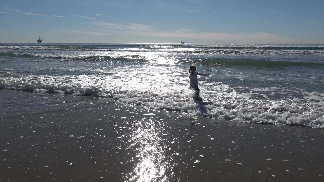 Young girl in the foamy edge of a wave on a bright beach.