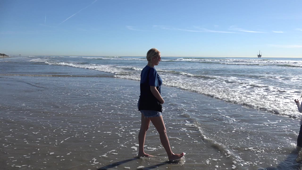 Woman near the shoreline with waves breaking behind her.