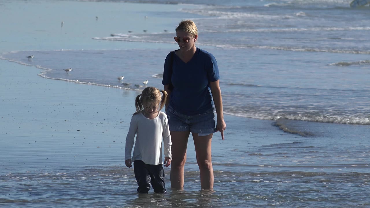 Woman and child continuing along the shoreline.