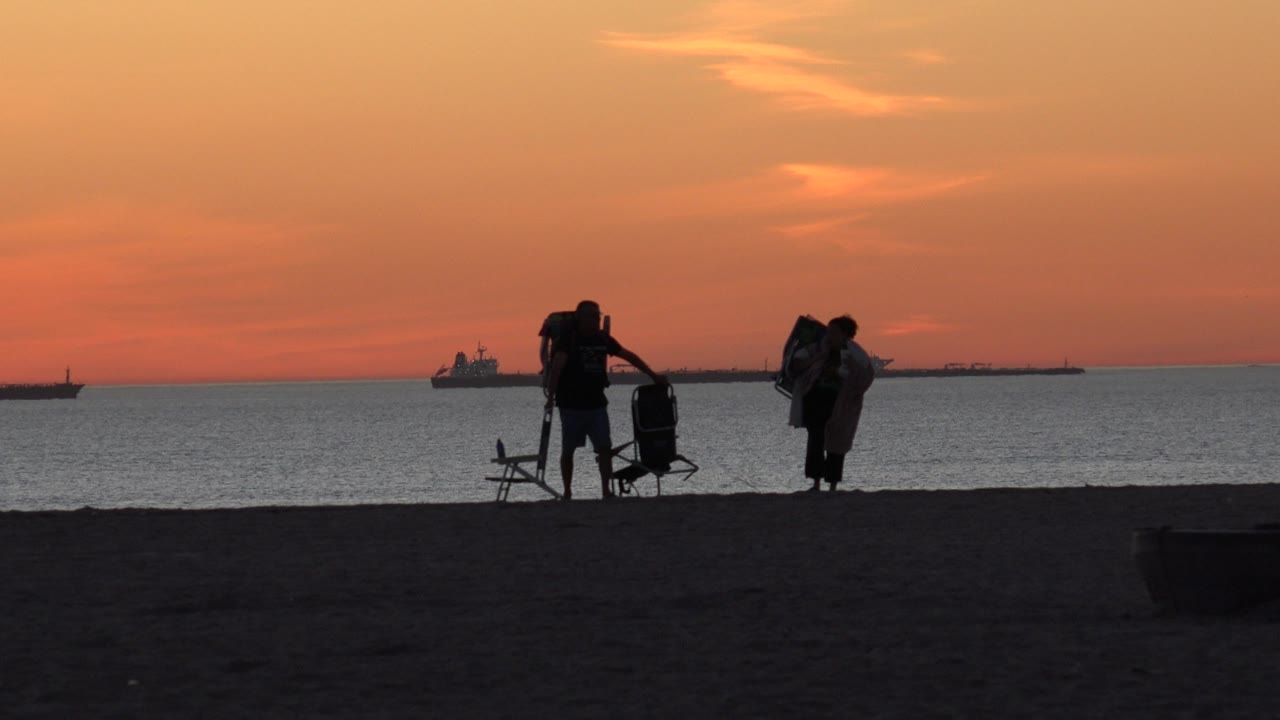 At Huntington Beach, the adults remain in silhouette near the waterline with a folding chair and carried packs visible against the orange sky.