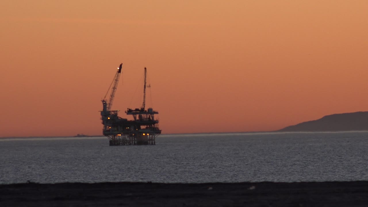 Offshore construction platform near the horizon with land visible at right.