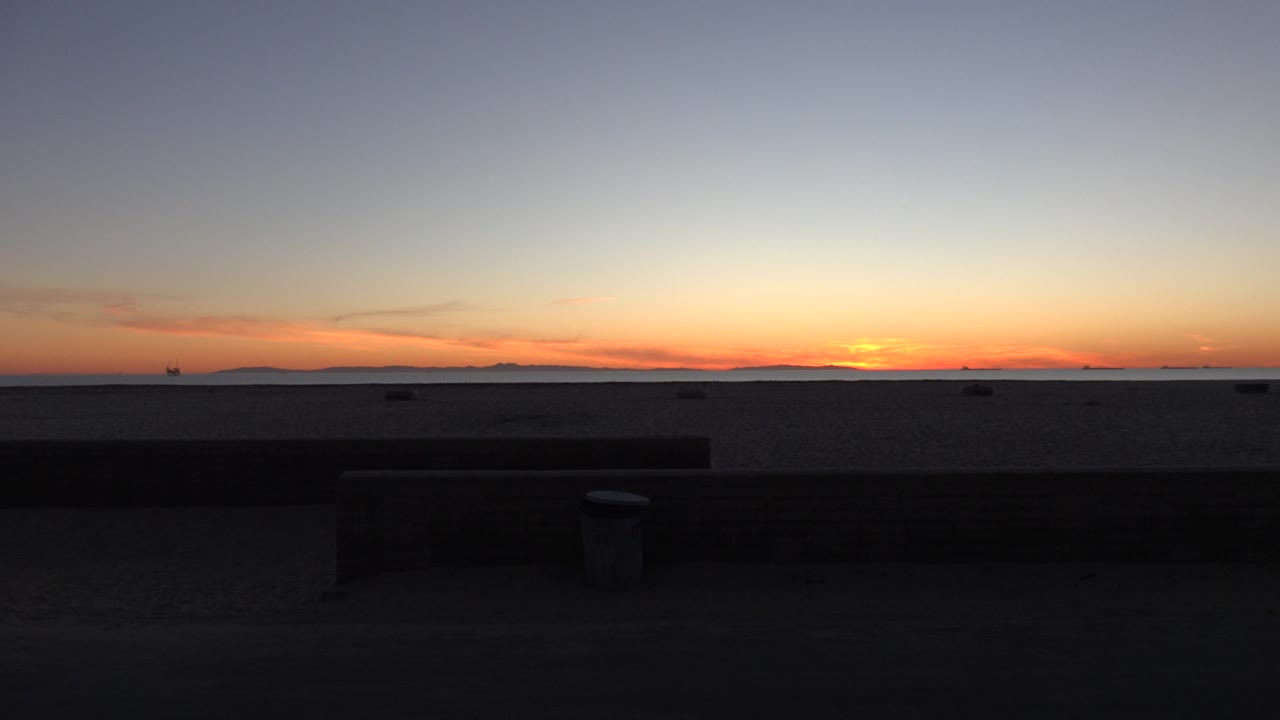 Dusk sky and ocean seen beyond a dark beach wall.