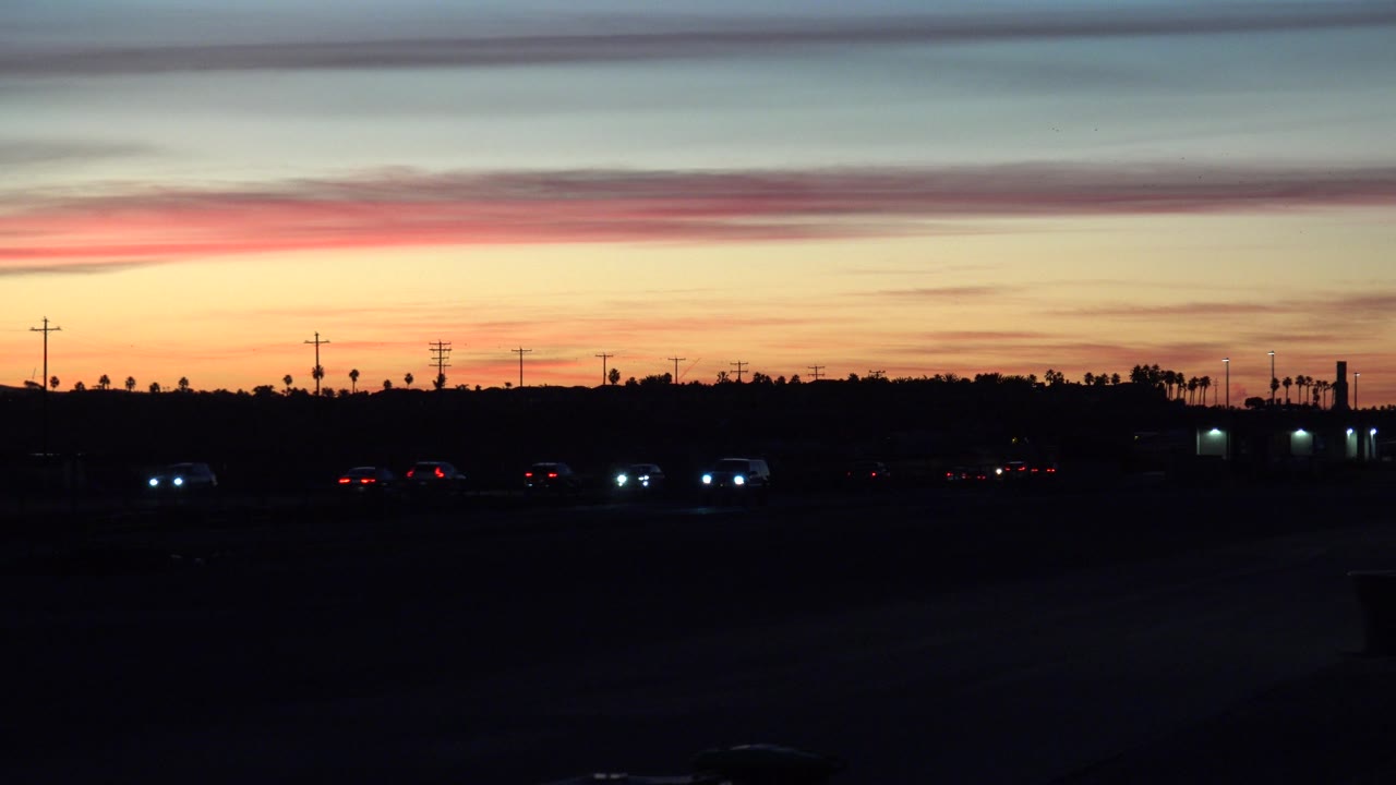 Dusk roadway with scattered car lights beneath a striped sunset sky.