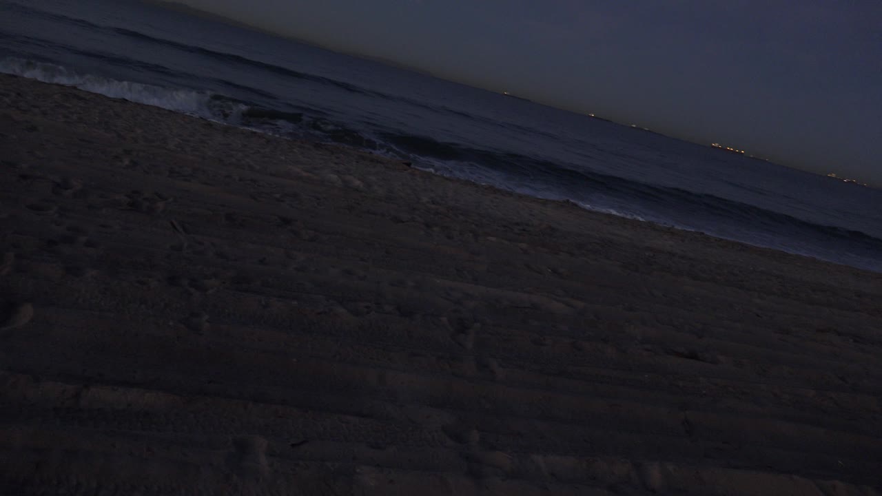 Dim beach and ocean with low waves at night