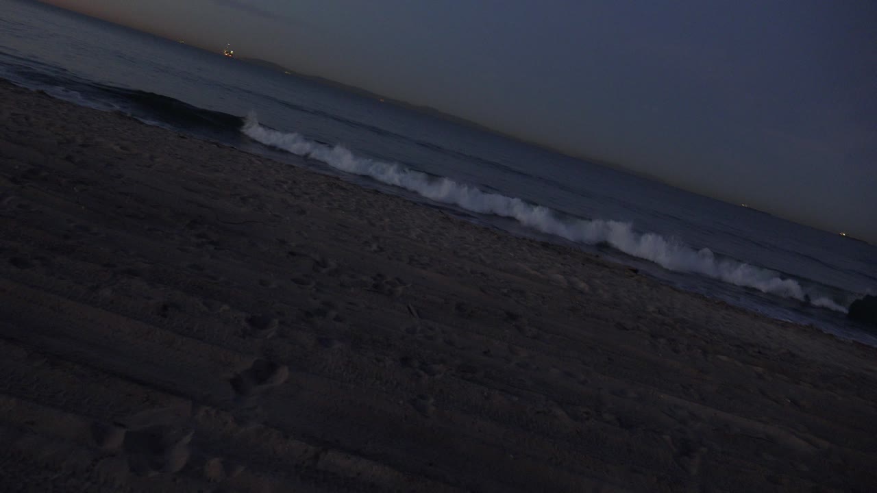 Wave crest breaking near the shoreline at dusk