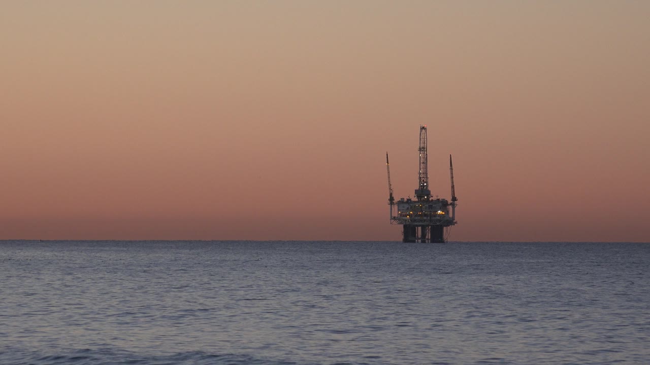 Offshore oil rig on the ocean horizon at sunset.
