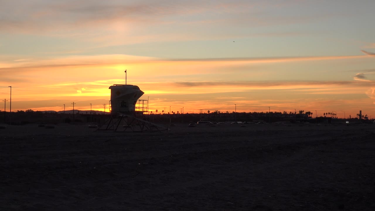 Dusk road scene with watchtower silhouetted below orange clouds.