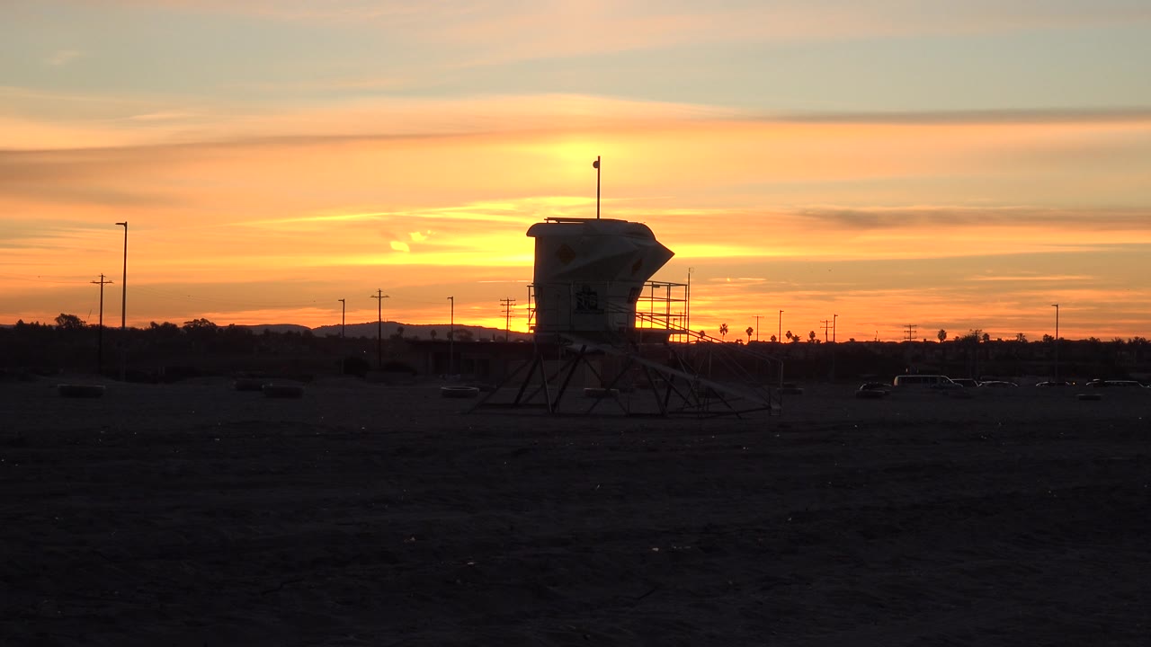 Beach tower silhouette and layered sunset clouds