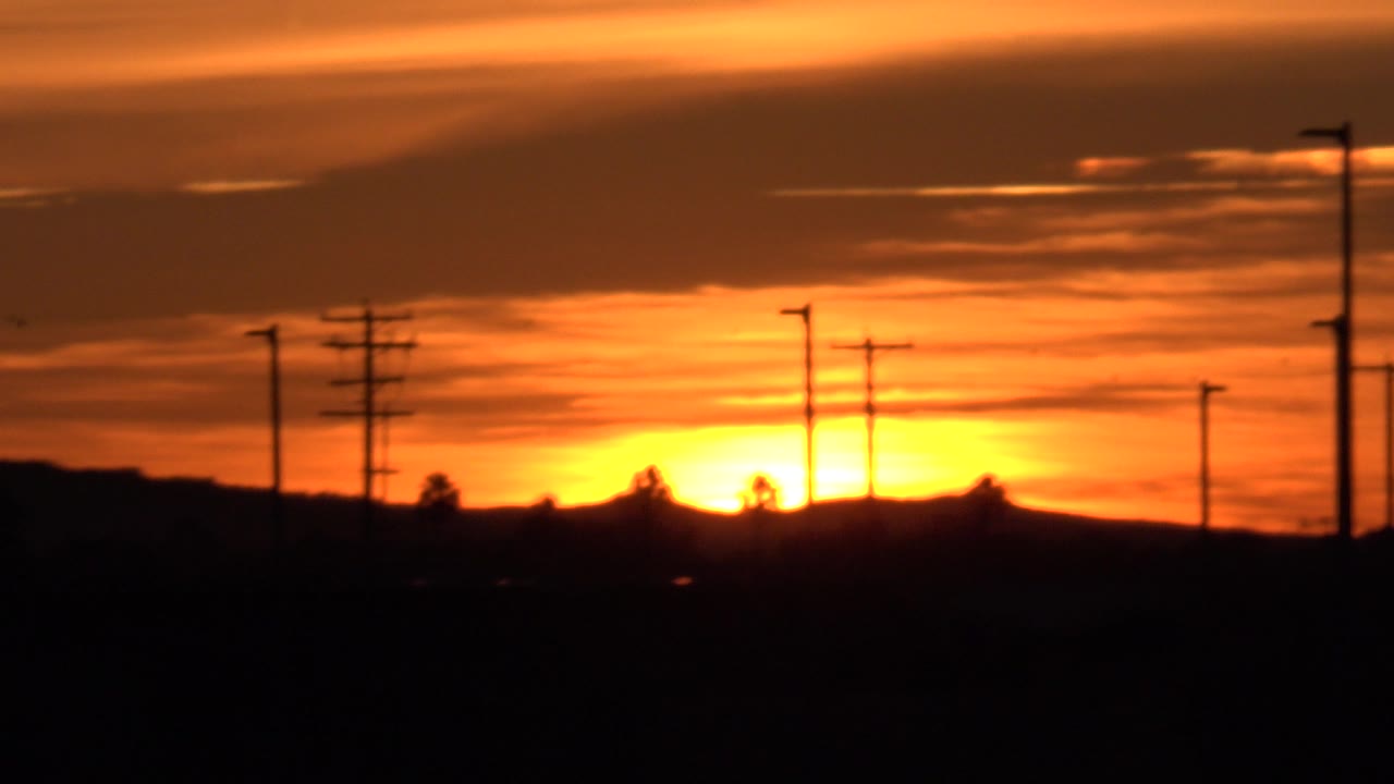 Sunset sky with utility poles and dark foreground.