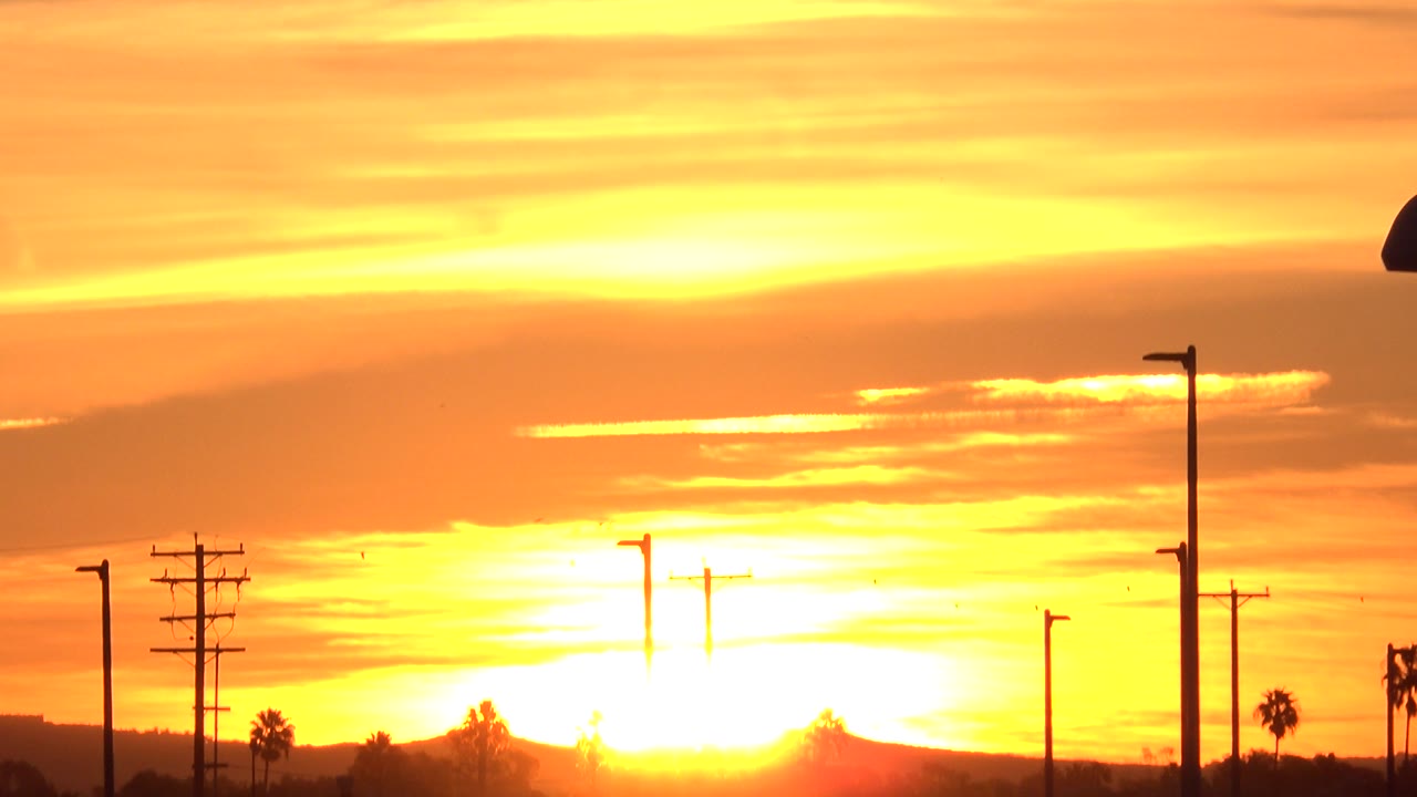 Bright sunset sky with silhouetted poles and distant horizon.