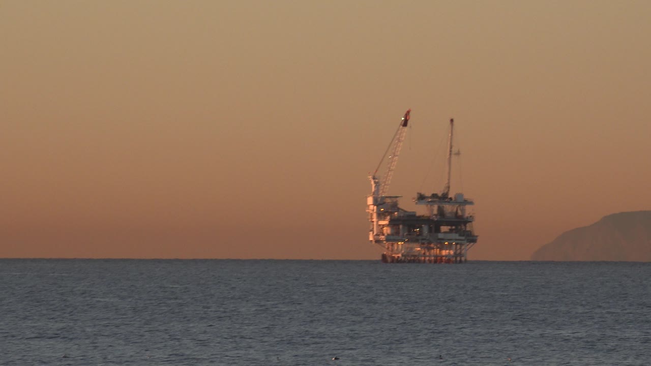 Offshore industrial structure near a hazy hill at sunset