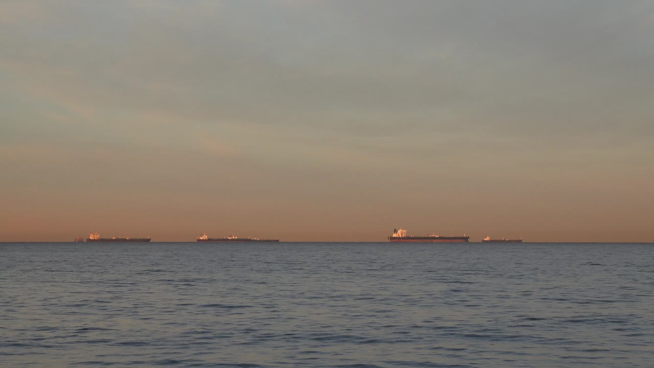 Open ocean foreground with multiple ships on the horizon.