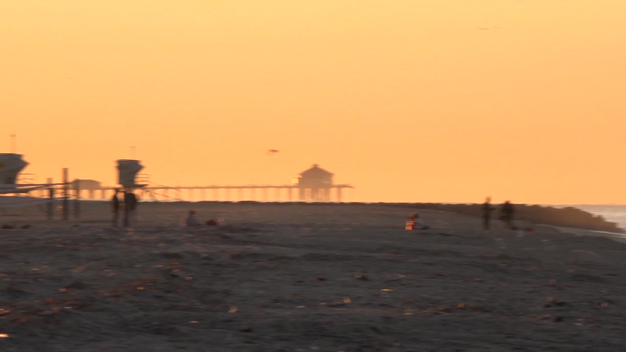 Dusk beach horizon with lifeguard tower and distant birds.