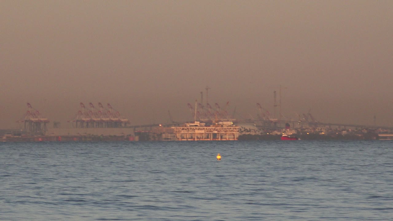 Yellow buoy in front of distant cargo port