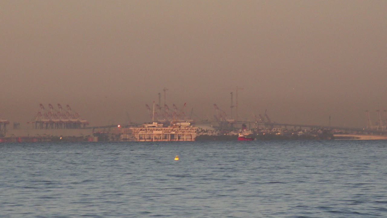 Distant ship mooring scene across calm ocean at sunset