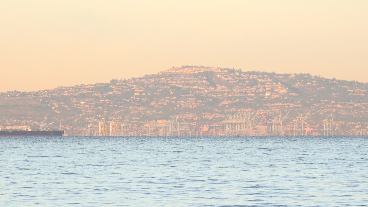 Blue ocean with hazy brown hillside across the horizon