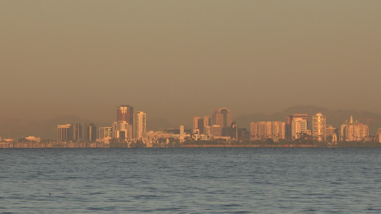 Orange-lit coastal skyline viewed from across open water.