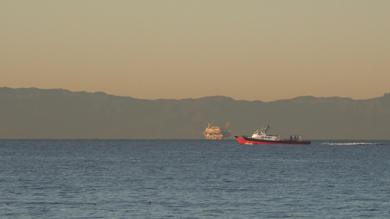 Boat near the right side of the frame with wake on open water.