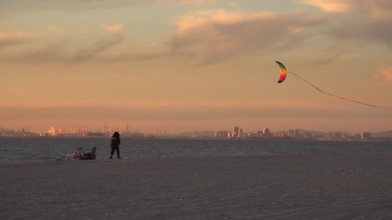 Colorful kite at upper right over a beach and distant shoreline.