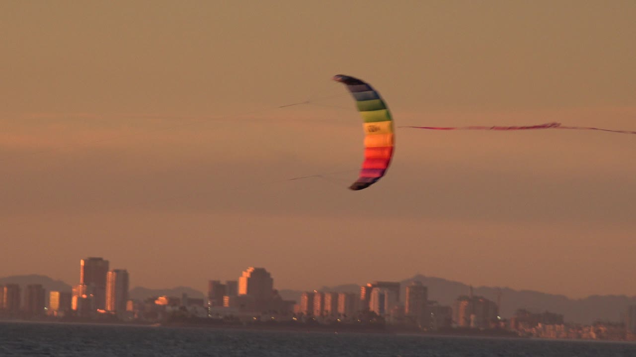 Multicolored kite over ocean with distant skyline