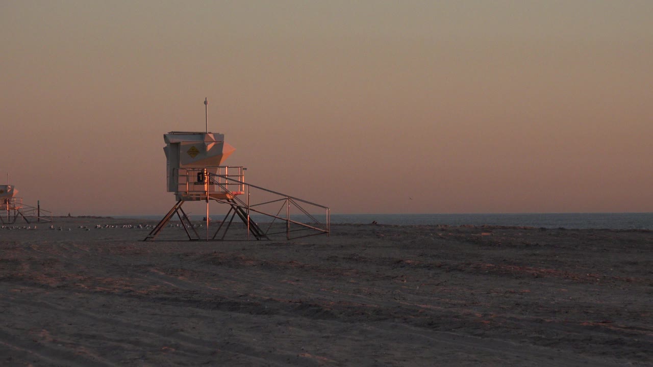 Lifeguard tower on dark sand near the ocean at dusk