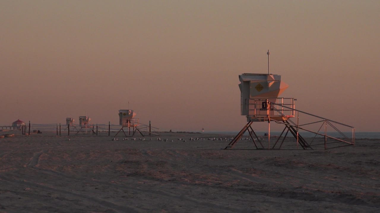 Raised box-like station on stilts near the right edge of the beach frame.