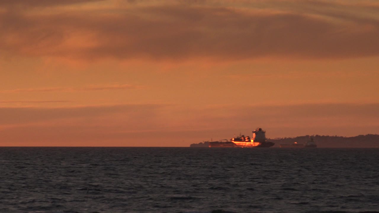 At Huntington Beach, California, the vessel appears slightly brighter against the dark horizon line, with rippled ocean foreground and no visible people.