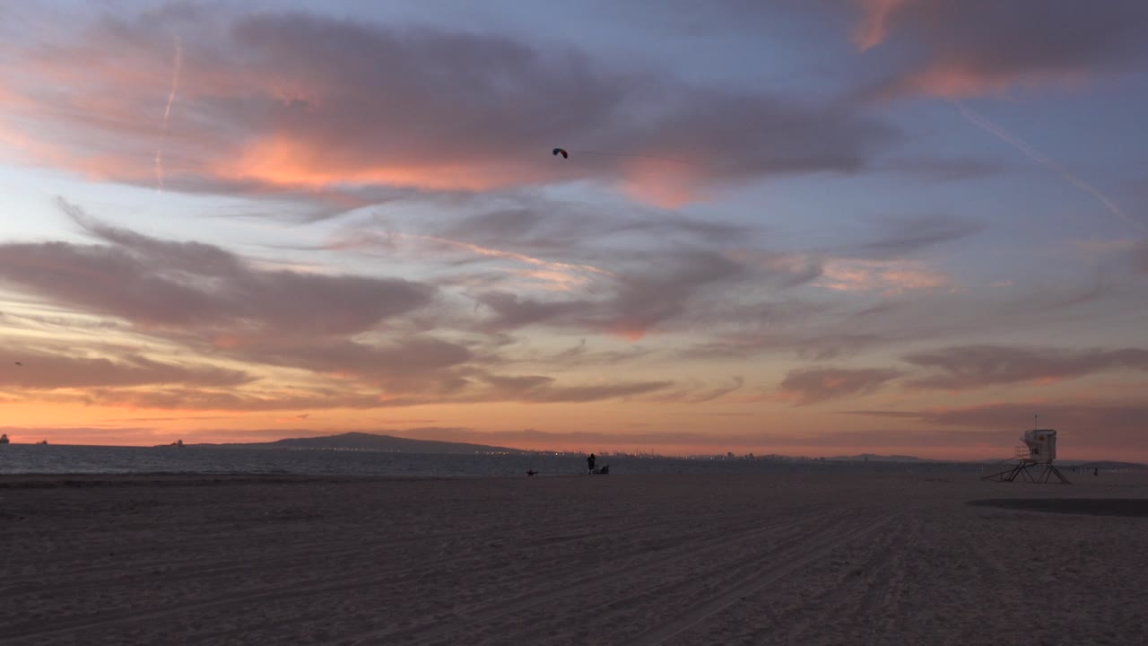 Low beach horizon beneath layered orange and gray clouds.