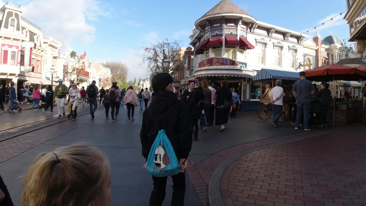 Crowd scene outside ornate storefronts with a child in the foreground.