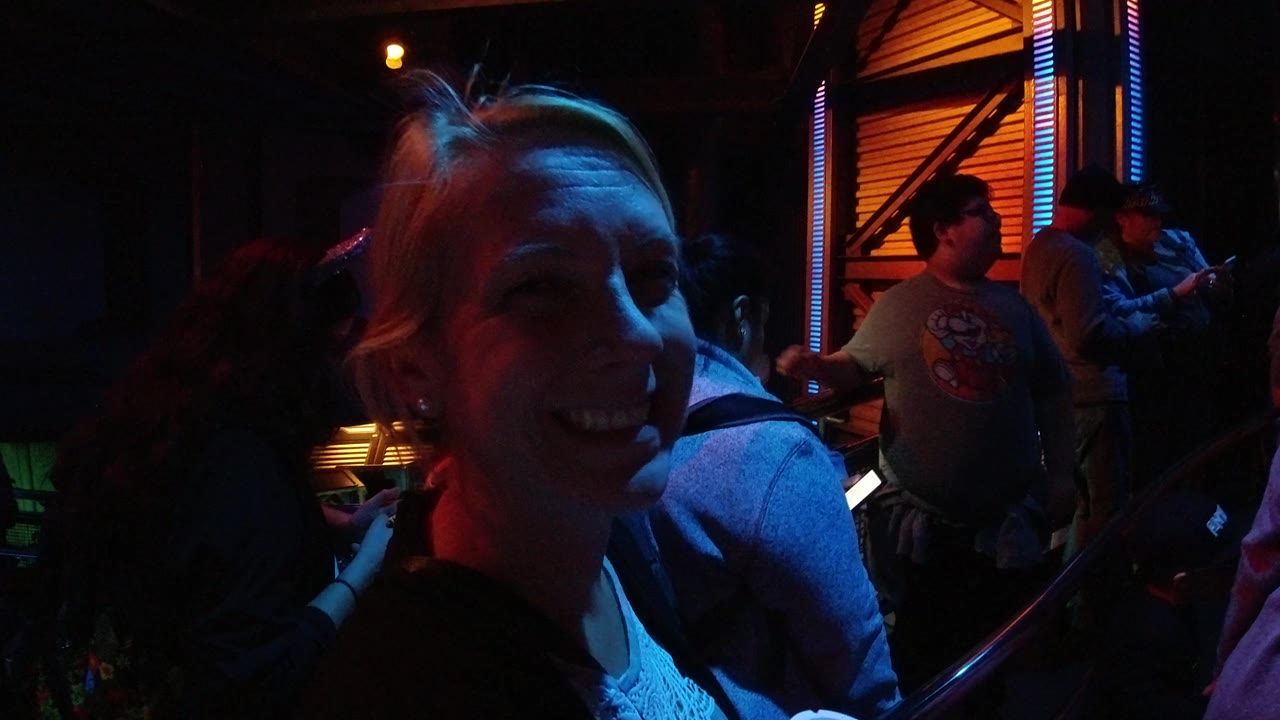 Young woman smiles near the lens while people wait in the background.