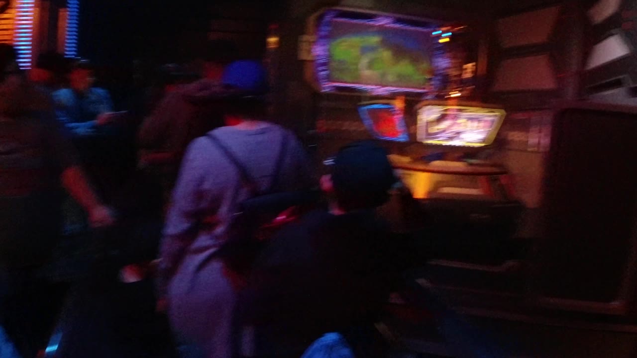 Guests face a glowing game display in a dim indoor room.