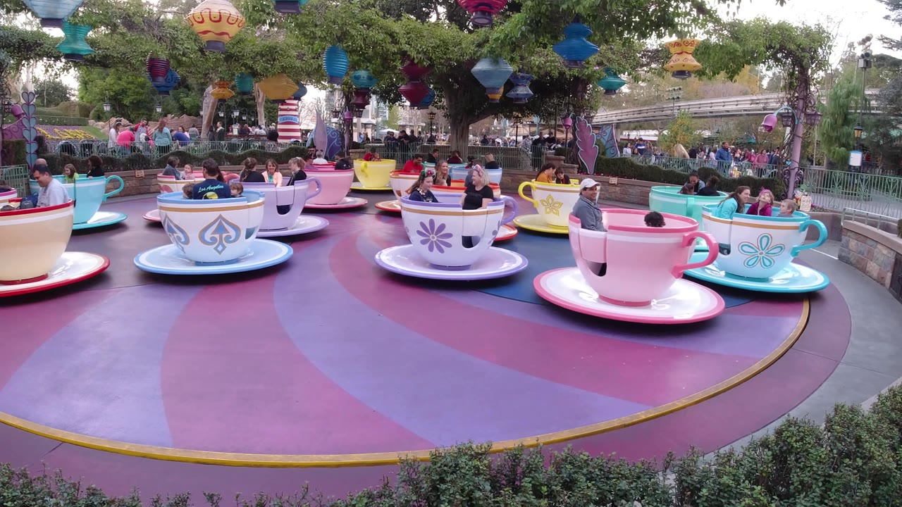Multiple teacup ride vehicles with families visible across the platform.
