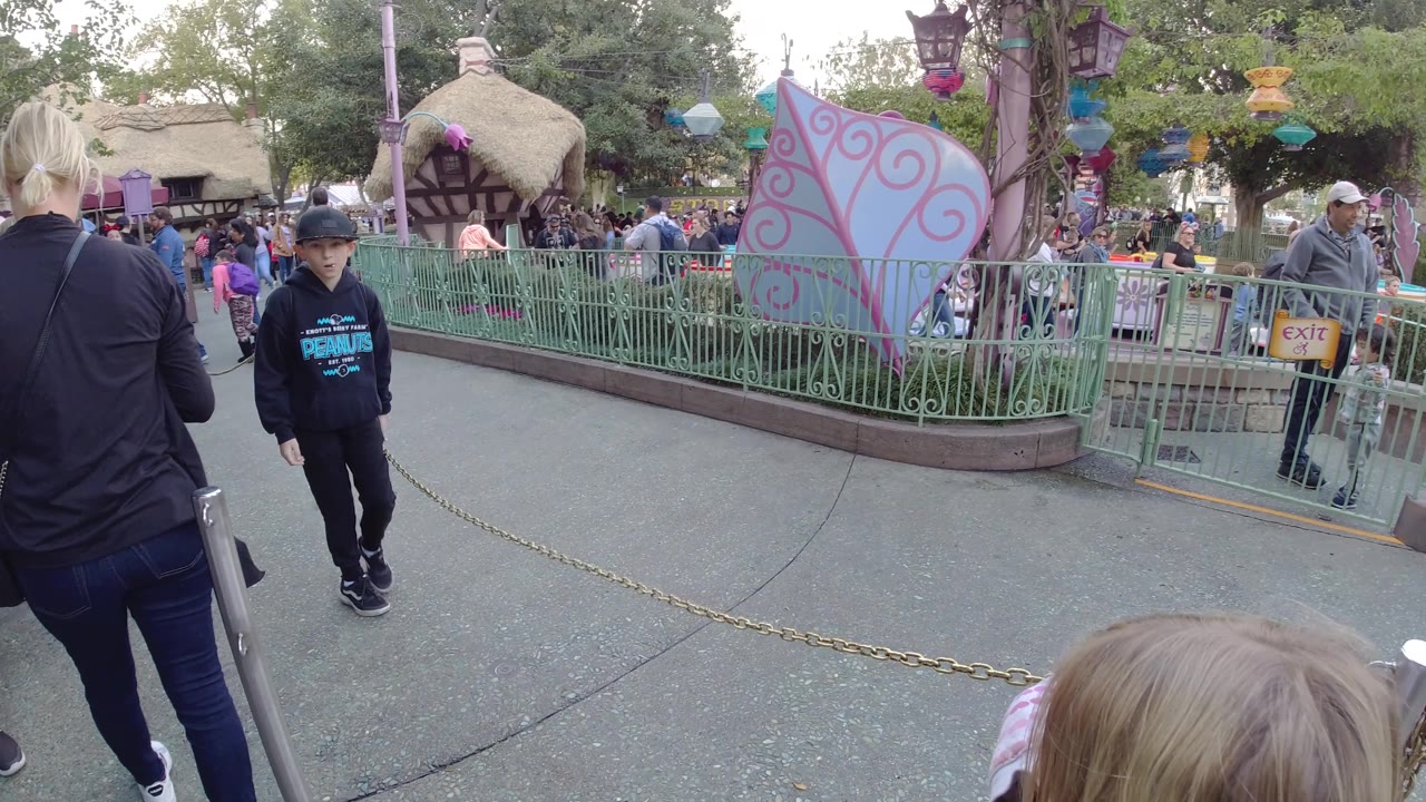 Boy in dark hoodie walks toward the camera near a chain barrier.