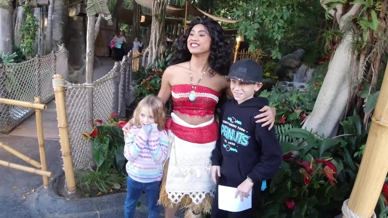 Costumed woman smiling with two children in a landscaped park area.