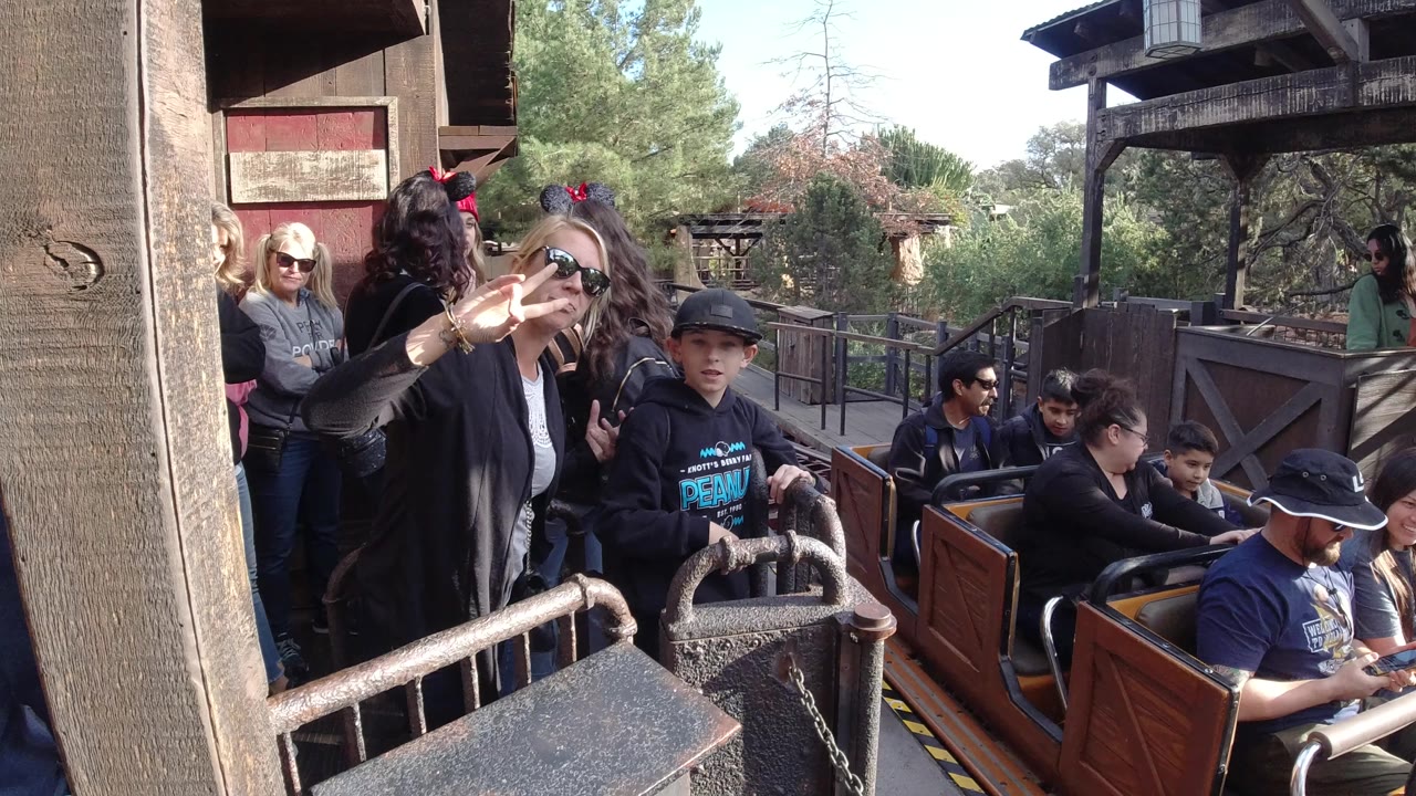 At Disneyland California, the coaster cars are still close to the station railings while several adults and children remain visible in the cars and on the platform.