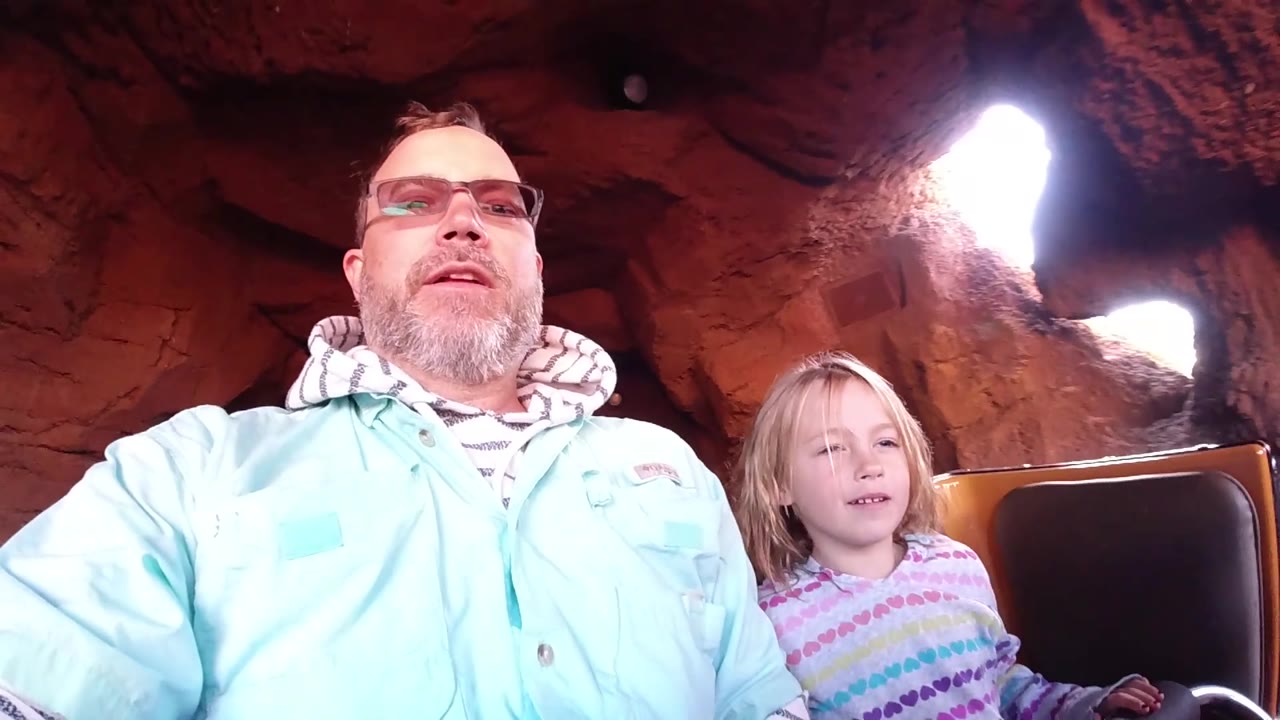 Father and daughter seated in the flume boat as the child looks forward.