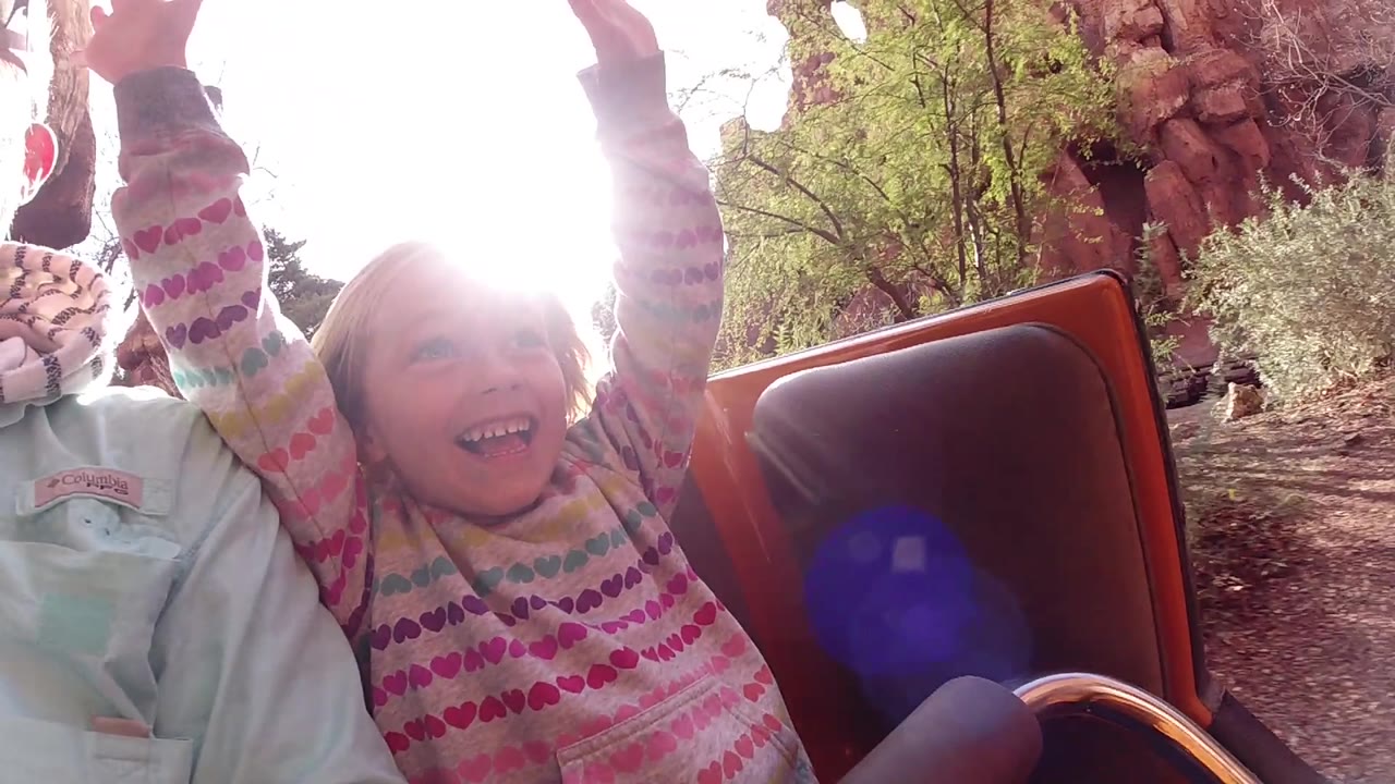 Backlit child smiling on amusement ride.