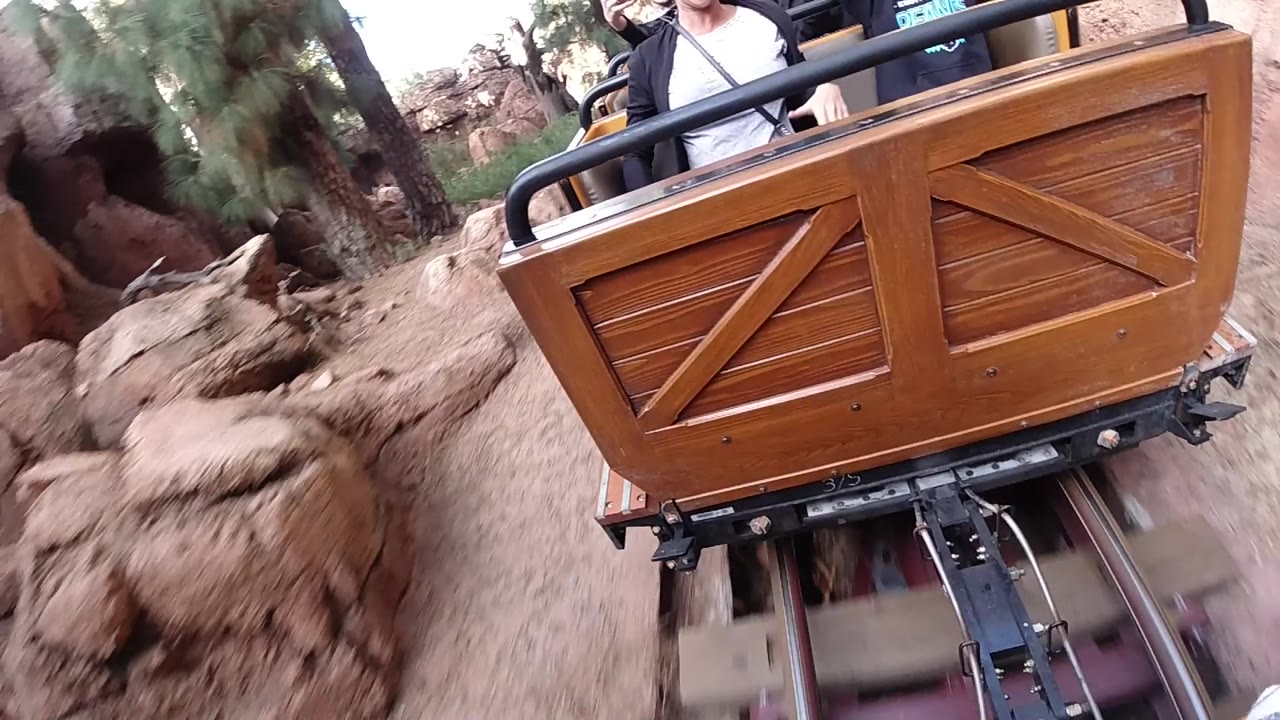 Close coaster cart tilted beside reddish rock walls.
