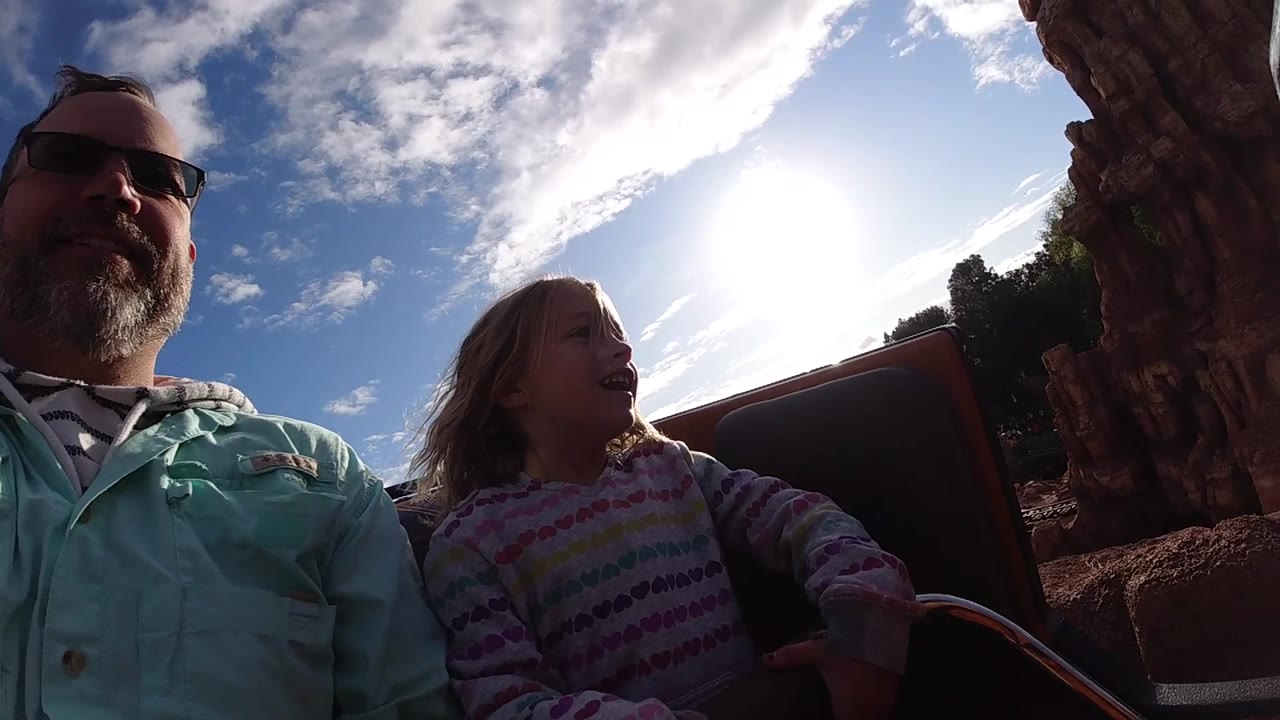 Close view of dad and daughter smiling on an amusement ride.